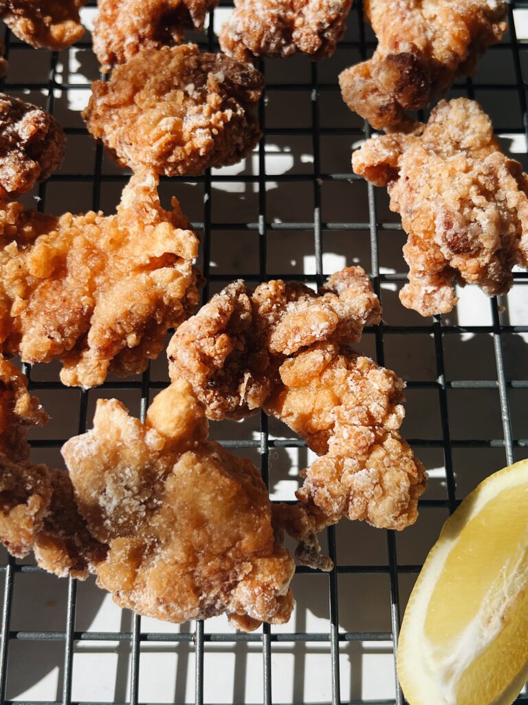 breaded and fried chicken on a wire rack with lemon slices.