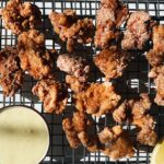 breaded and fried chicken with lemon slices and sauce on a wire rack