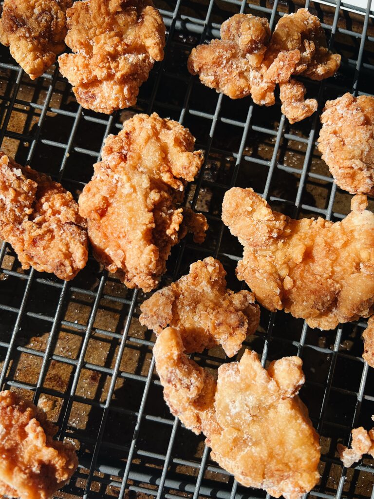 breaded and fried chicken with lemon slices and sauce on a wire rack