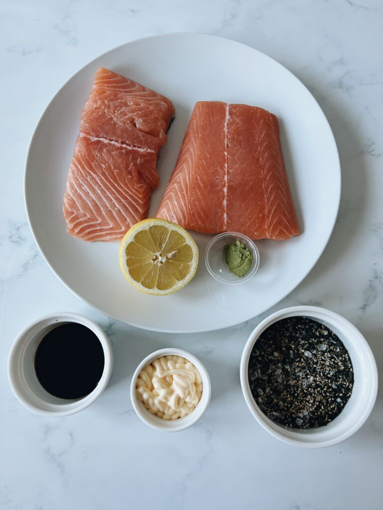 salmon, lemon, wasabi, soy sauce, furikake and mayonnaise all in separate containers in a flat lay
