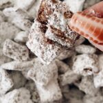 Muddie buddies in a cluster with a finger and nail holding it up to the camera with more muddy buddies in the background